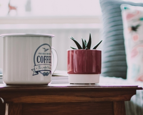 Wochenrückblick — Kaffeetasse kleine Pflanze auf Beistelltisch
