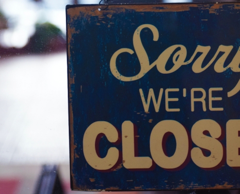 Schild, das im Fesnter eines Geschäfts hängt. Auf diesem steht "sorry, we're closed"